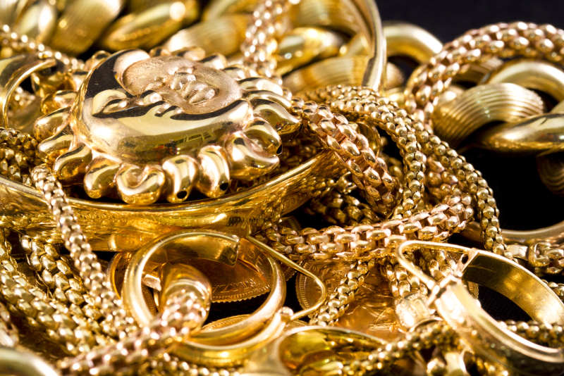 Image by Lapas77 via ShutterStock - Closeup of yellow gold jewelery on a black background